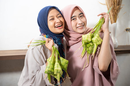 Excited asian muslim woman making ketupat rice with coconut leaf during ramadan kareem preparing for...