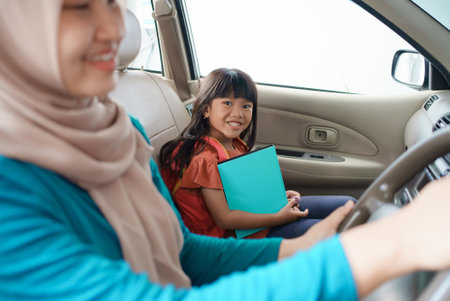 asian muslim mother taking her daughter to school in the morning by car. happy student going back to schoolの写真素材