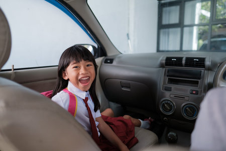 happy asian primary student while going to school by car with parent in the morningの写真素材