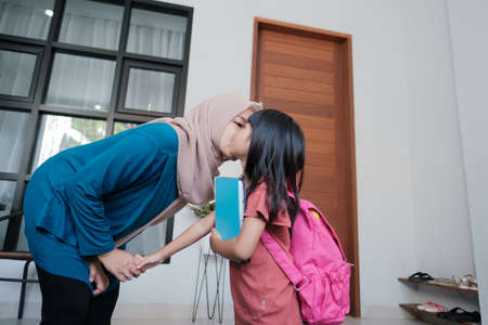 portrait of happy muslim mother kiss her kid cheek in the morning at home before school dayの写真素材