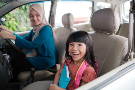 asian muslim mother taking her daughter to school in the morning. happy student going back to schoolの写真素材