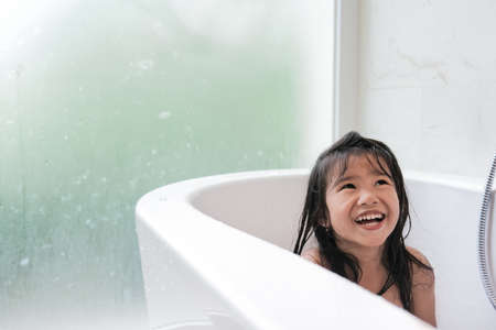 happy asian girl taking a bath together on a bathtubの写真素材