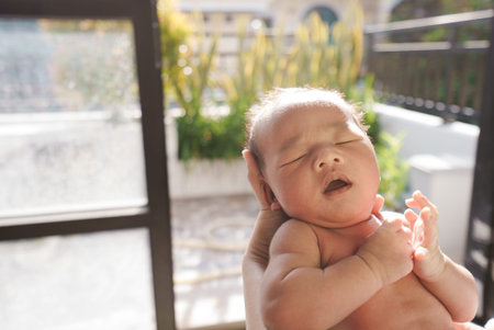 portrait of new born baby sun bathing under the morning sun at home next to windowの写真素材