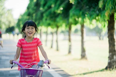 little girl enjoy Ride Bike In the park. asian kid