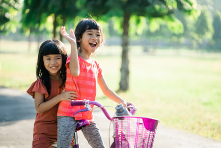 two kids enjoy Ride Bike In the park together. asian kidの写真素材