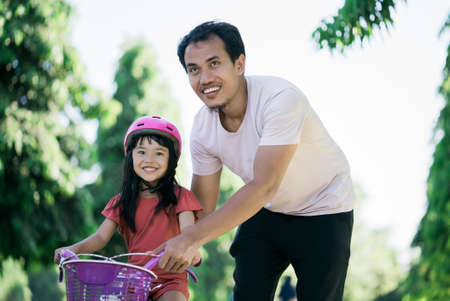 asian Father Teaching daughter To Ride Bike In the parkの写真素材