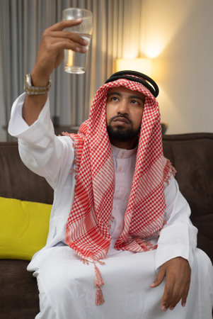 An Arab in a turban lifts a glass filled with water and lifts it up to be seen when breaking the fastの写真素材