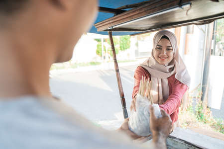 muslim woman taking her food order from chicken satay street food sellerの写真素材
