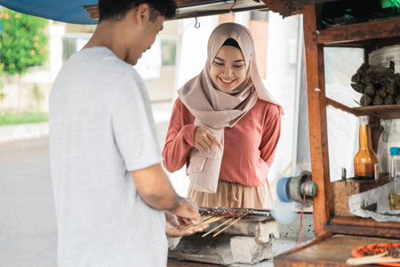 muslim woman ordering chicken satay on the street food sellerの写真素材
