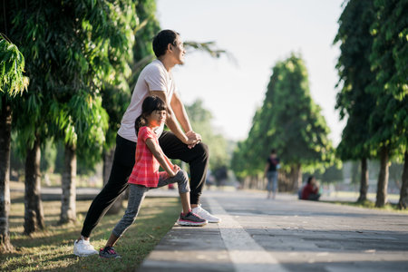 asian father and daughter stretching and sport outdoor together in the park