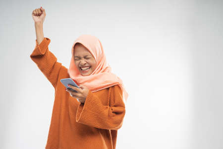 a girl wearing a veil stood holding a cellphone with a raised hand with copyspace in the isolated backgroundの写真素材