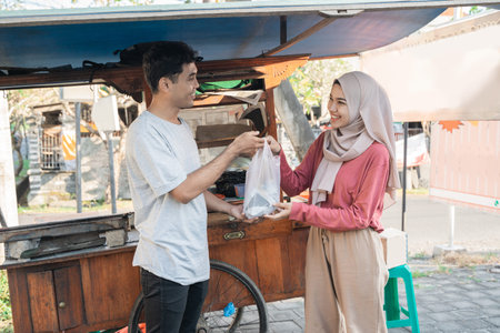 muslim woman taking her food order from chicken satay street food seller
