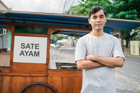 man street food seller of chicken satay with food cart selling sate ayam. proud of small business...