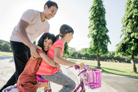 asian Father Teaching daughter To Ride Bike In the parkの写真素材