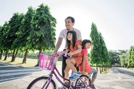 asian Father Teaching daughter To Ride Bike In the parkの写真素材