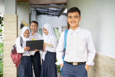 a teenager smiles at the camera in a school uniform carrying a school bag with copyspace in an outdoor backgroundの写真素材