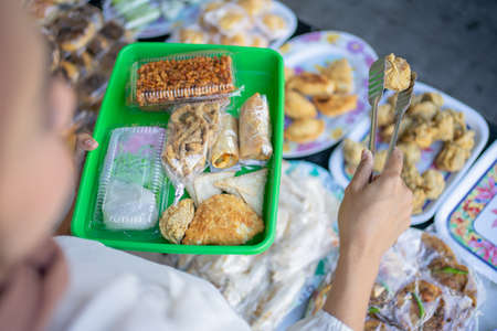 female buyer uses tong tongs to select and take the fried food to the plastic tray before placing the plastic bagの写真素材
