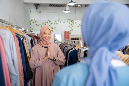 A waitresses in a veil with welcome gesture when the customer arrives to a boutique shopの写真素材