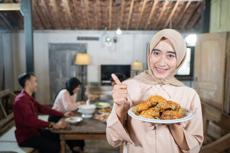 woman in veil carrying a plate of fried chicken with thumbs up in the background family members...