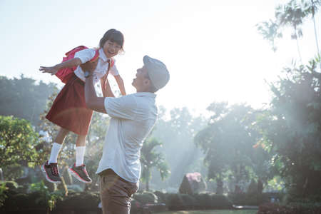 proud dad raise her daughter up to the sky. back to school indonesian primary school studentの写真素材
