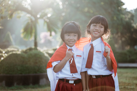 two indonesian school student holding flag during independence day. proud primary pupil with...