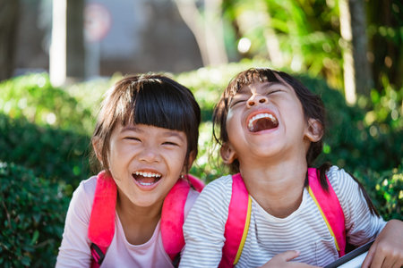 happy cute asian kid student laughing while sitting in the park