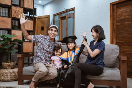 Kindergarten graduation. Happy asian family graduate at home. elementary school student at home celebratingの写真素材