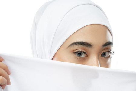 beautiful eyes of hijab woman in white veil with a cloth against white background