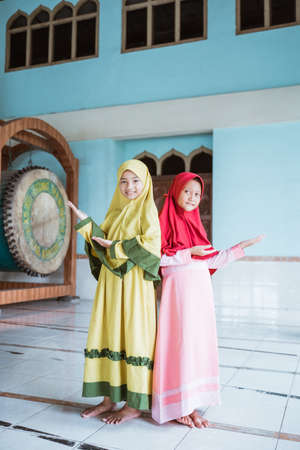 Two kid girl asian Muslim smiling showing somethingの写真素材