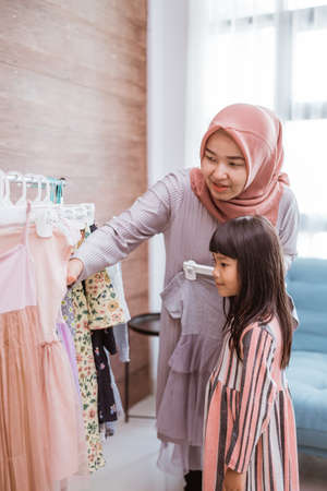 mother muslim choosing a dress for her daughter at clothing storeの写真素材