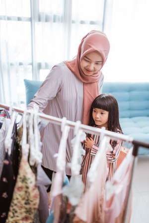 mother muslim choosing a dress for her daughter at clothing storeの写真素材