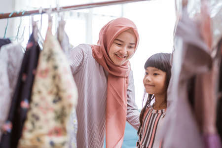 mother muslim choosing a dress for her daughter at clothing storeの写真素材