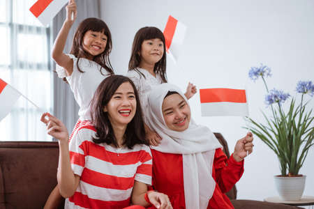 excited indonesian family supporter while watching sport match at television at homeの写真素材