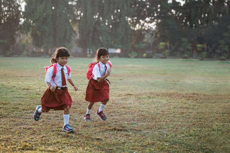 little girl student running together while going to their schoolの写真素材
