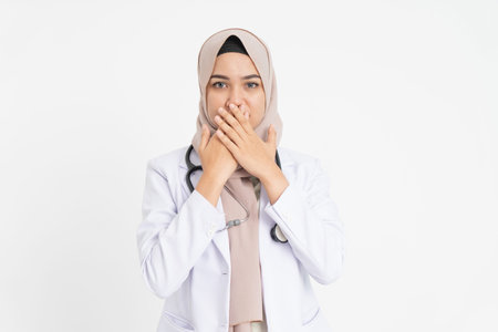 female doctor wearing white suit uniform covering her mouth with both hands