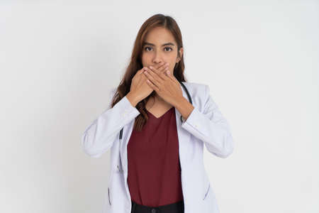 female doctor wearing white suit uniform covering her mouth with both handsの写真素材