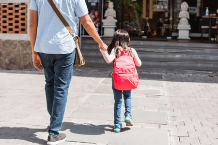 father taking a walk with his daughter to schoolの写真素材