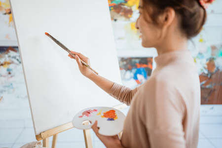 painter artist painting on canvas shoot from her backの写真素材