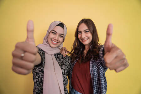 close up of faces of two smiling women looking at camera with thumbs up gestureの写真素材