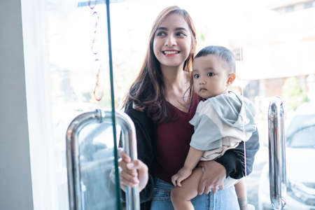 asian mother with her toddler boy entering shopping mallの写真素材