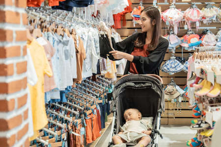 indonesian mother shopping clothes for her son in the baby boutique storeの写真素材