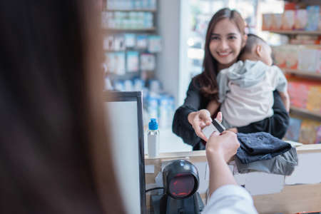 mother making a payment at the baby shop using credit cardの写真素材