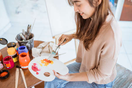 asian female artist painting on canvas doing art projects on her studioの写真素材