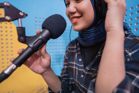 muslim woman girl is recording a podcast in her studioの写真素材