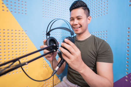 happy asian man is recording a podcast in his studioの写真素材