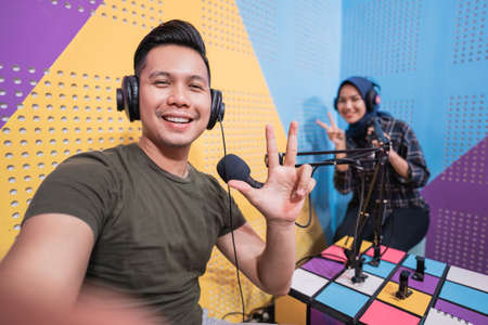 couple in podcast studio taking a selfie with their phone togetherの写真素材