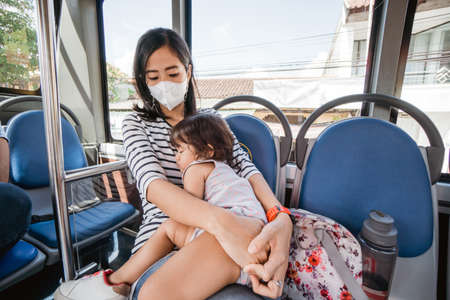 baby sleeping on mothers lap while in public busの写真素材