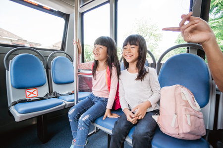 two asian primary student going to school by bus public transport