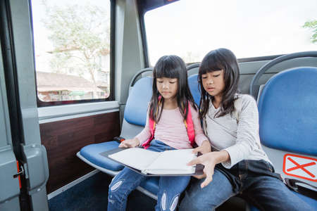 two asian primary student going to school by bus public transportの写真素材
