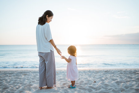 girl from behind and a white dress standing on a summer beach looking at sunsetの写真素材